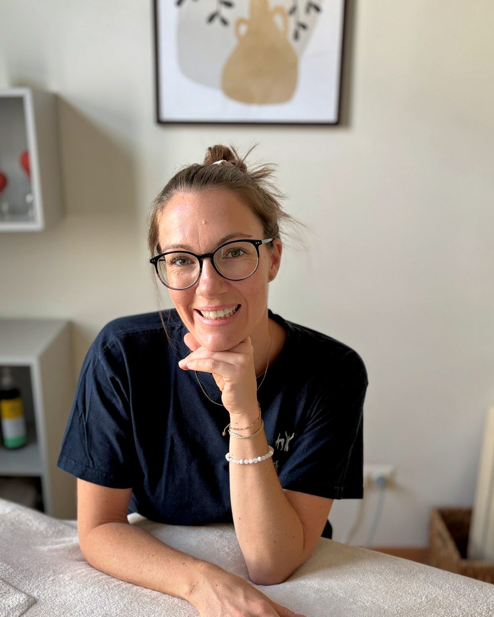 Kerstin König in ihrem Therapieraum, aufgestützt auf die Behandlungsliege